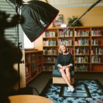 long camera angle into a library room with a interviewee on a chair